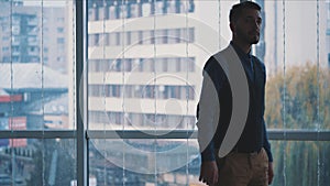 Businessman in formal suite stands in front of panoramic window with city view. Close up. Slow motion. Slowmo. 4K.