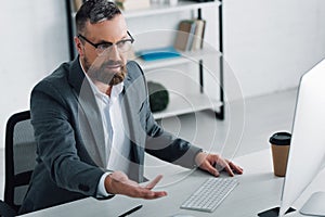 Businessman in formal wear talking in video chat in office