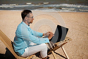 Businessman freelance on beach sitting with laptop.