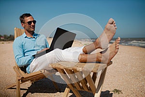 Businessman freelance on beach sitting with laptop.