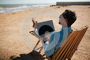 Businessman freelance on beach sitting with laptop.