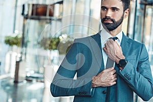 Businessman in a fromal suit in a business center tighten a tie