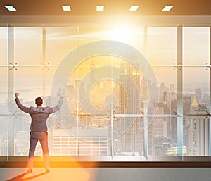 Businessman in front of office window thinking of new challenges