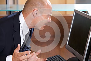 Businessman frowning in front of computer monitor
