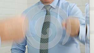 Businessman gesticulate in bathroom playing in mirror scissor rock paper game