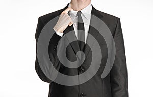 Businessman and gesture topic: a man in a black suit and tie holding a hand to his shirt collar isolated on a white background in