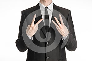 Businessman and gesture topic: a man in a black suit with a tie showing a sign with his right hand two or three left hand sign iso