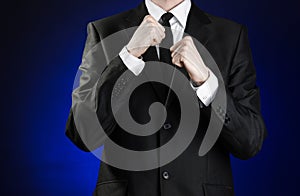 Businessman and gesture topic: a man in a black suit and white shirt holding his fists in front of him on a dark blue background