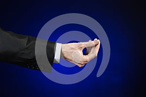 Businessman and gesture topic: a man in a black suit and white shirt showing hand gesture on an isolated dark blue background in