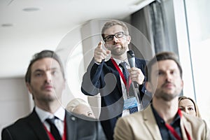 Businessman gesturing while asking question during seminar