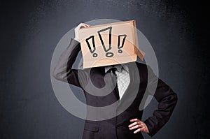 Businessman gesturing with a cardboard box on his head with exclamation point