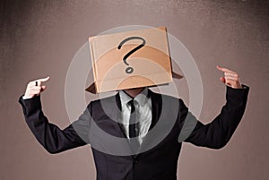 Businessman gesturing with a cardboard box on his head with ques