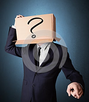 Businessman gesturing with a cardboard box on his head with ques