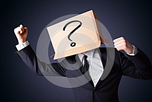 Businessman gesturing with a cardboard box on his head with ques