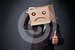 Businessman gesturing with cardboard box on his head with sad fa