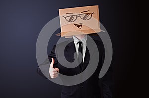 Businessman gesturing with a cardboard box on his head with smiley face