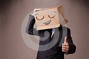 Businessman gesturing with a cardboard box on his head with smiley face