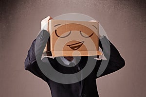 Businessman gesturing with a cardboard box on his head with smiley face