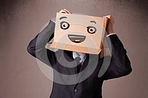 Businessman gesturing with a cardboard box on his head with smiley face