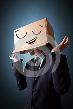 Businessman gesturing with a cardboard box on his head with smiley face