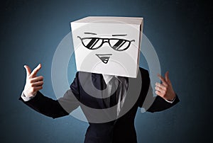 Businessman gesturing with a cardboard box on his head with smiley face