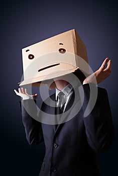 Businessman gesturing with a cardboard box on his head with stra