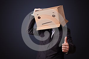 Businessman gesturing with a cardboard box on his head with straight face