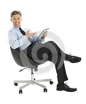 Businessman Gesturing At Digital Tablet While Sitting On Office