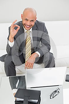 Businessman gesturing okay sign with laptop at home