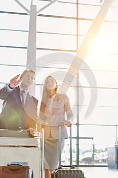 Businessman gesturing and talking to young attractive businesswoman  while queuing for check in at airport