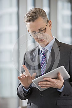 Businessman gesturing while using digital tablet in office