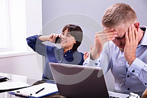 Businessman Getting Irritated With Colleague Talking On Phone