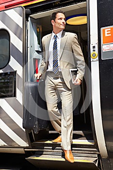 Businessman Getting Off Train At Platform