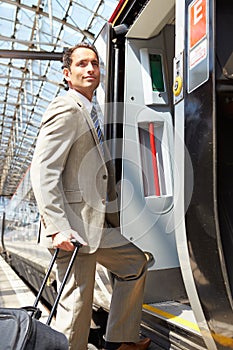 Businessman Getting On Train At Platform