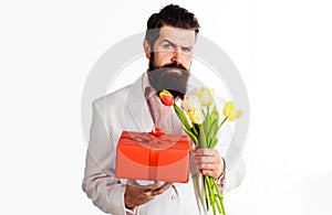 Businessman with gift and bouquet of tulips. Handsome man with present and flowers. Birthday, Valentines Day, Womens Day