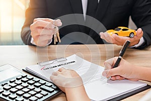 Businessman giving car key and customer signing loan agreement w