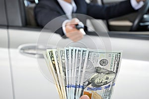 Businessman giving a car key exchanging with money