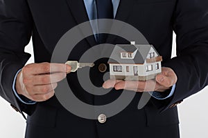 Businessman giving a key and holding small house