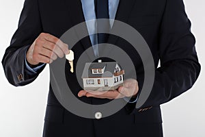 Businessman giving a key and holding small house