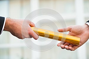 Businessman Giving Relay Baton To Colleague