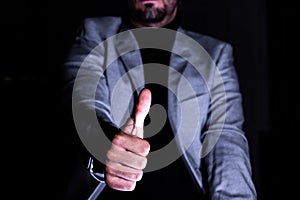 Businessman giving thumbs up in low light
