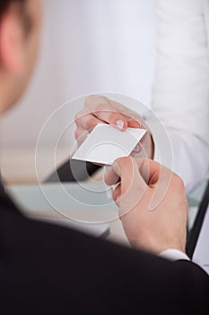 Businessman Giving Visiting Card To Colleague At Desk