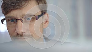 Businessman with glasses looking intently obscured partially by a translucent surface of laptop. Business concept