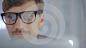 Businessman with glasses looking intently obscured partially by a translucent surface of laptop. Business concept