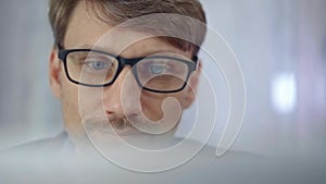 Businessman with glasses looking intently obscured partially by a translucent surface of laptop. Business concept