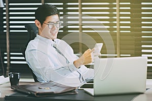 Businessman in glasses sitting at office desk with laptop