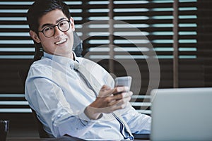 Businessman in glasses sitting at office desk with laptop