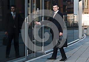Businessman goes to work. handsome man in a business suit opens the door to the office in a business center. mid-level manager.