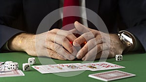Businessman at green gaming table with game chips, cards and dice playing poker and blackjack in casino