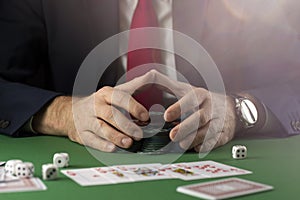 Businessman at green gaming table with game chips, cards and dice playing poker and blackjack in casino